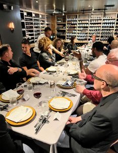 Guests gather for an elegant dinner surrounded by fine wine and lively conversation.