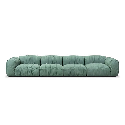 A large green sectional sofa with soft, ruched upholstery and low wide cushions, designed for comfort and modern style, displayed against a plain white background.