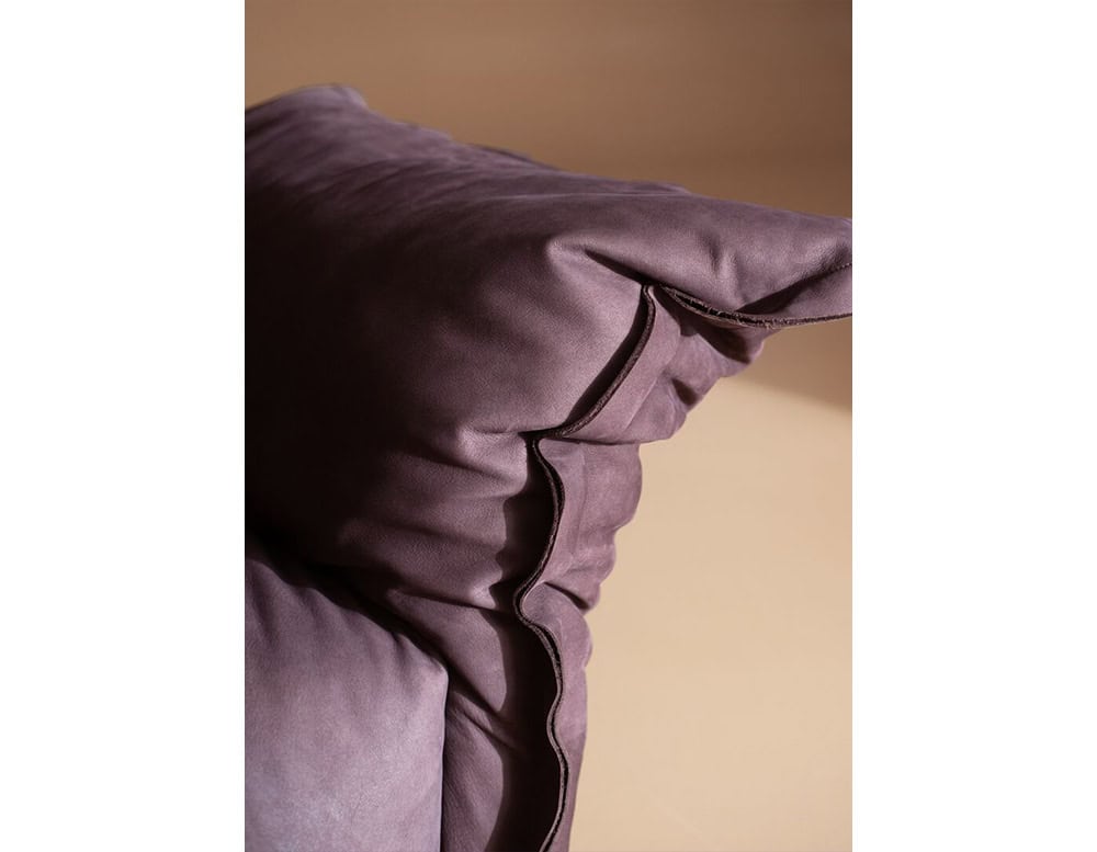 Contemporary armchair in rich purple fabric featuring generous cushioning, loose casual stitching and inviting texture for a modern yet comfortable look.