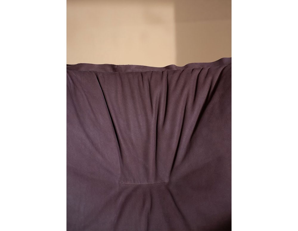 Detailed view of the armchair’s backrest fabric in rich purple, featuring subtle folds and stitching that emphasize the seat’s relaxed and inviting design.