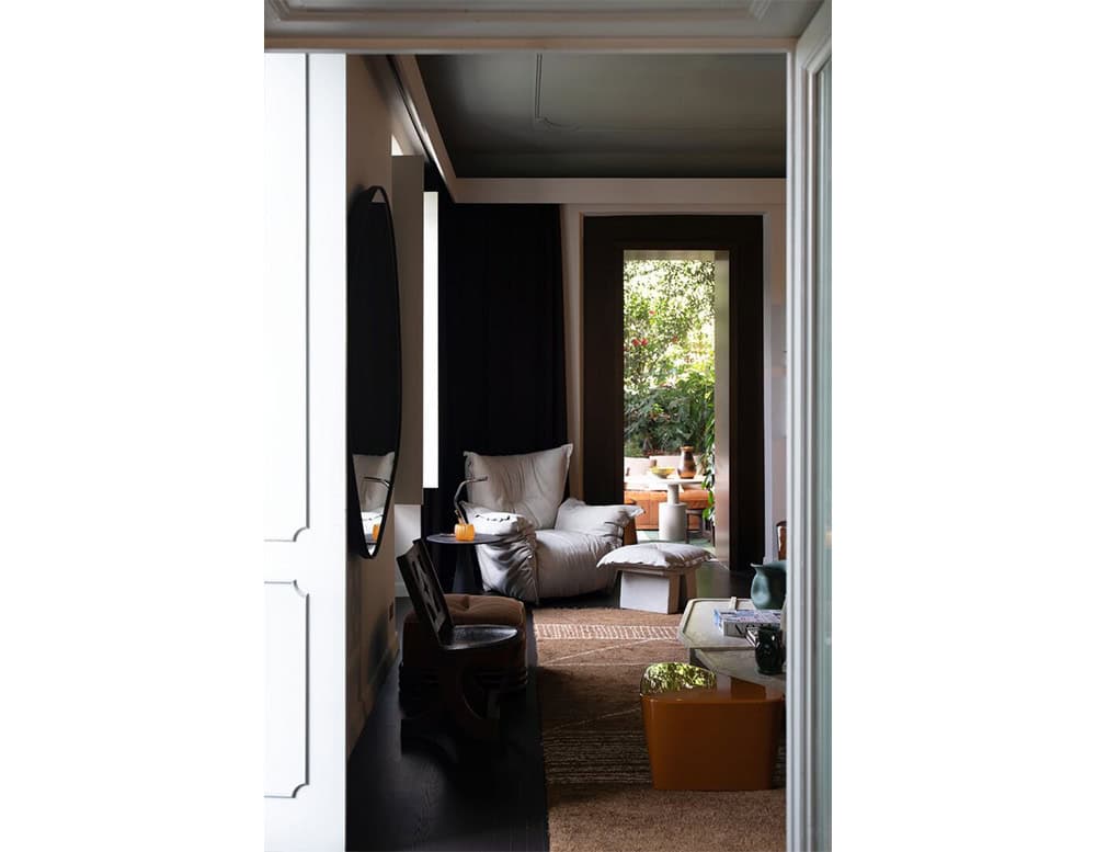 Elegant seating arrangement with a plush armchair and ottoman near a bright window paired with a small round side table for a calm and inviting space.