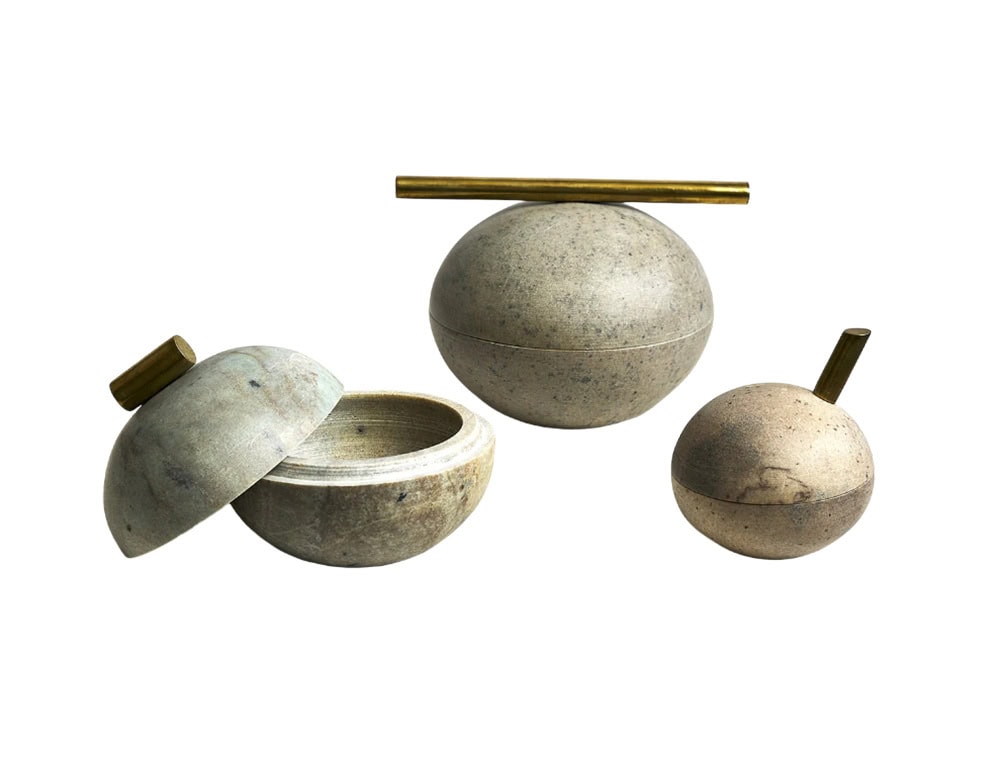 Bola Sabao Accessories feature smooth stone spheres in natural beige tones, accented with brass handles that add elegance and a contemporary edge.