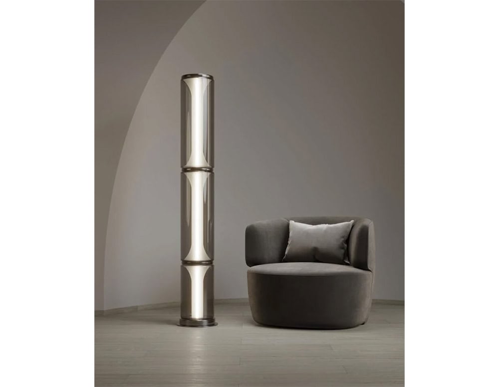 A tall floor light composed of stacked smoked glass cylinders with soft, warm illumination, adding a sculptural and contemporary presence to any room.