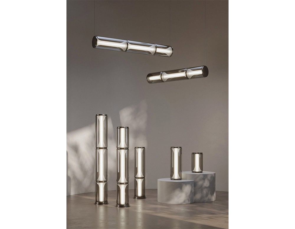 A modular lighting installation with smoked glass cylinders in various heights and hanging forms, creating a sculptural and atmospheric glow for contemporary spaces.