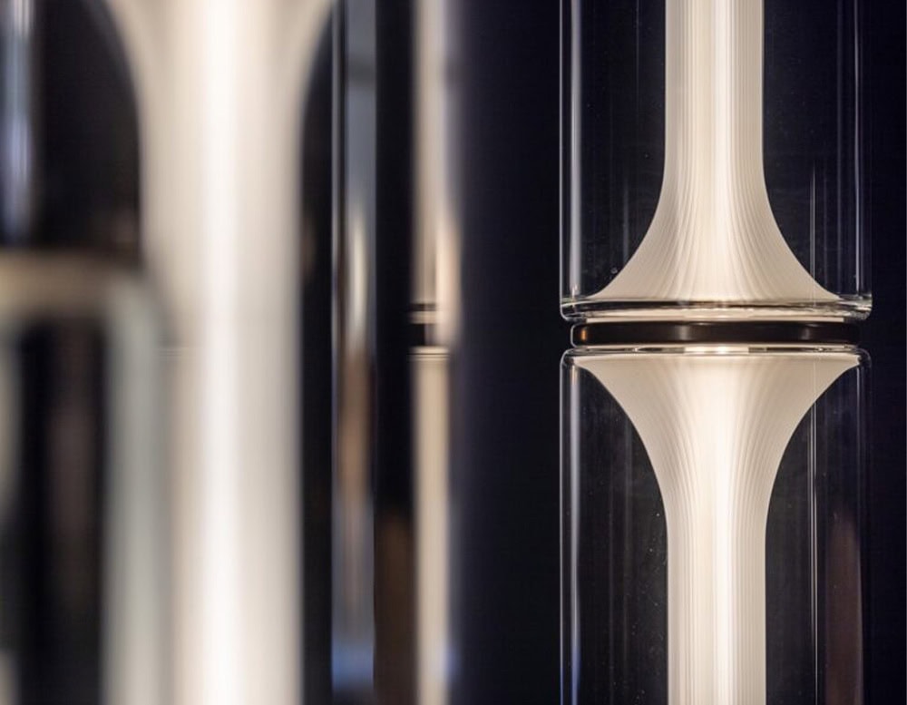 Las Miles Lighting captures an intimate view of the glowing glass cylinder, highlighting its soft curves, layered textures, and the gentle diffusion of light within its sculptural form.