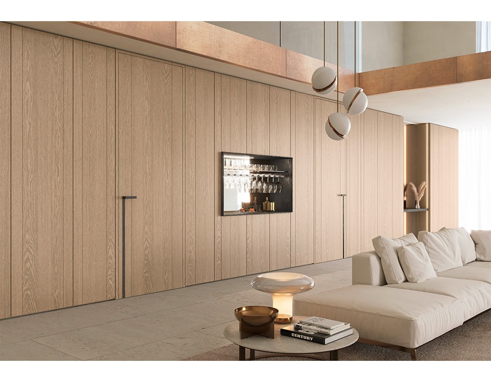 This wall unit blends hidden storage with a sophisticated built-in bar niche featuring glassware organization and elegant lighting.