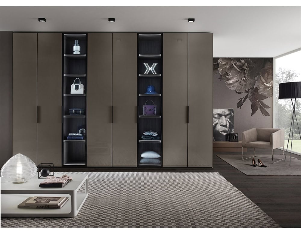 A contemporary wardrobe system featuring minimalist panel doors flanked by illuminated shelving, designed to display personal items with style.