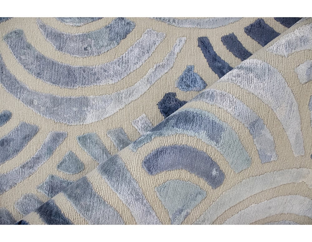 A close look at the Cancun rug reveals intricate pile work with layered arcs in shades of blue and cream. The soft textures and detailed craftsmanship highlight its refined artistry and oceanic inspiration.