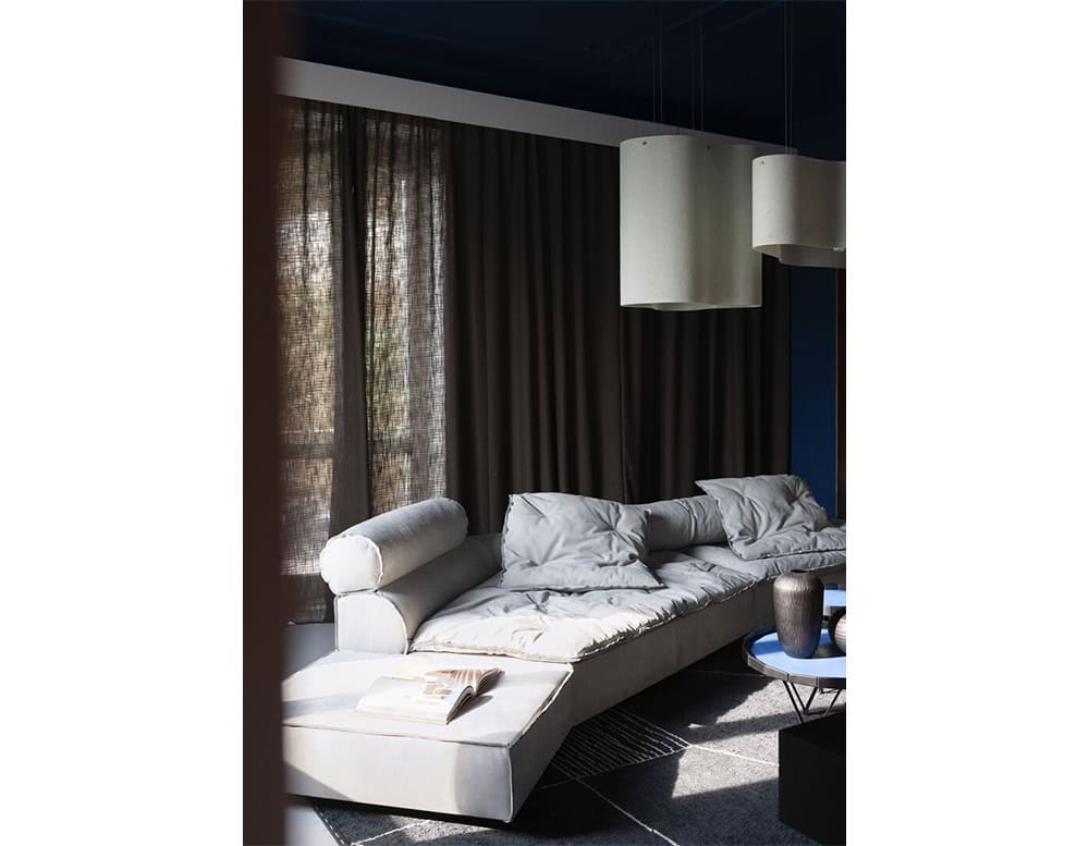 Designed in soft gray tones, this modular sofa with wide seats and plush bolsters creates a relaxed lounge atmosphere enhanced by textured cushions and a low black coffee table for balance and contrast.