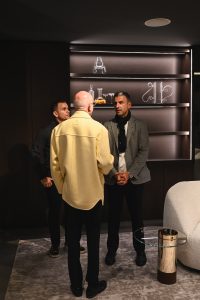 Guests gather in a quiet corner of the showroom, sharing conversation surrounded by soft lighting and refined design accents that set the tone for the evening.