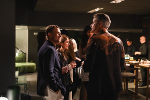 Guests trade stories and smiles as the evening unfolds, capturing the effortless charm and lively energy of the showroom gathering.