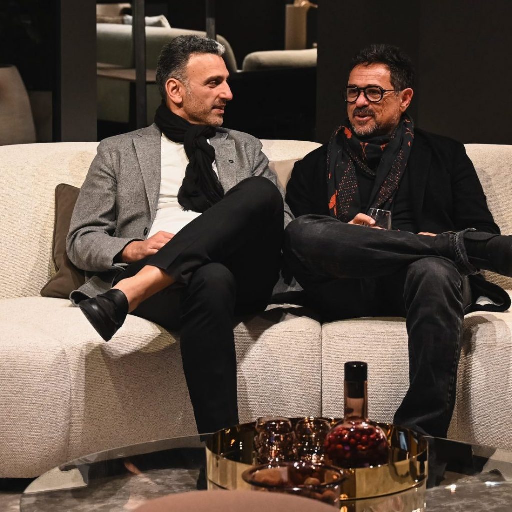 Two guests settle into one of the showroom’s signature sofas, enjoying an easy conversation surrounded by soft light and refined design details that capture the spirit of the evening.