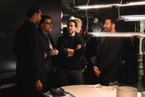 Guests gather around a sleek display, chatting over drinks as the modern lighting sets the tone. The showroom’s atmosphere invites easy conversation and a shared appreciation for design.