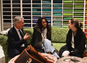 A cozy conversation unfolds on a plush sofa as guests share smiles and stories surrounded by colorful textiles that set the tone for a warm and creative evening in the showroom.