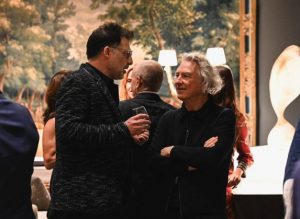 Two guests enjoy a relaxed conversation, drinks in hand, surrounded by warm lighting and the elegant ambiance of the event.