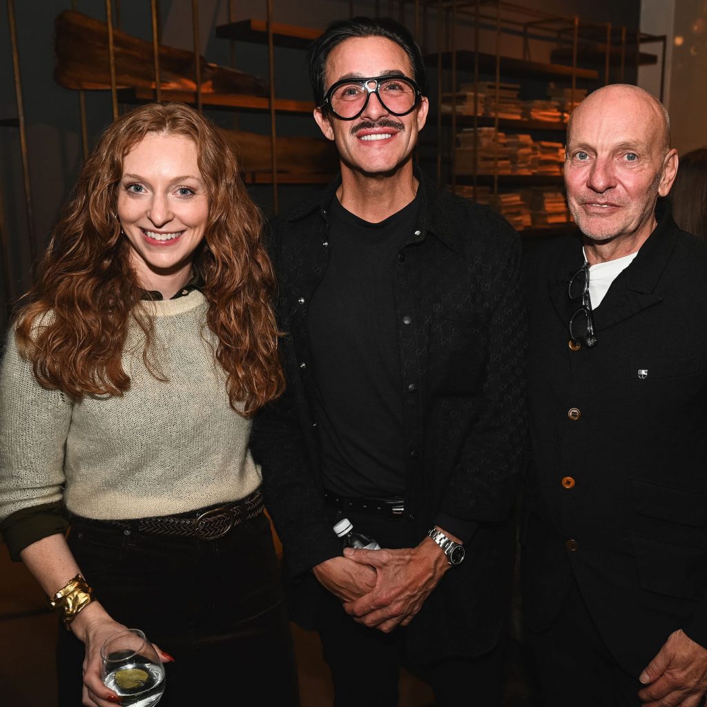 Smiling guests gather inside the elegant showroom, enjoying drinks and conversation surrounded by artful lighting and sculptural furniture displays. The moment captures the friendly energy that filled the evening.