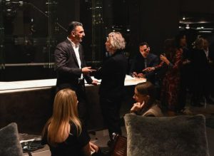 Warm conversations flow around a sleek display as guests pause to connect, surrounded by soft lighting and elegant textures that highlight the inviting ambiance of the showroom gathering.