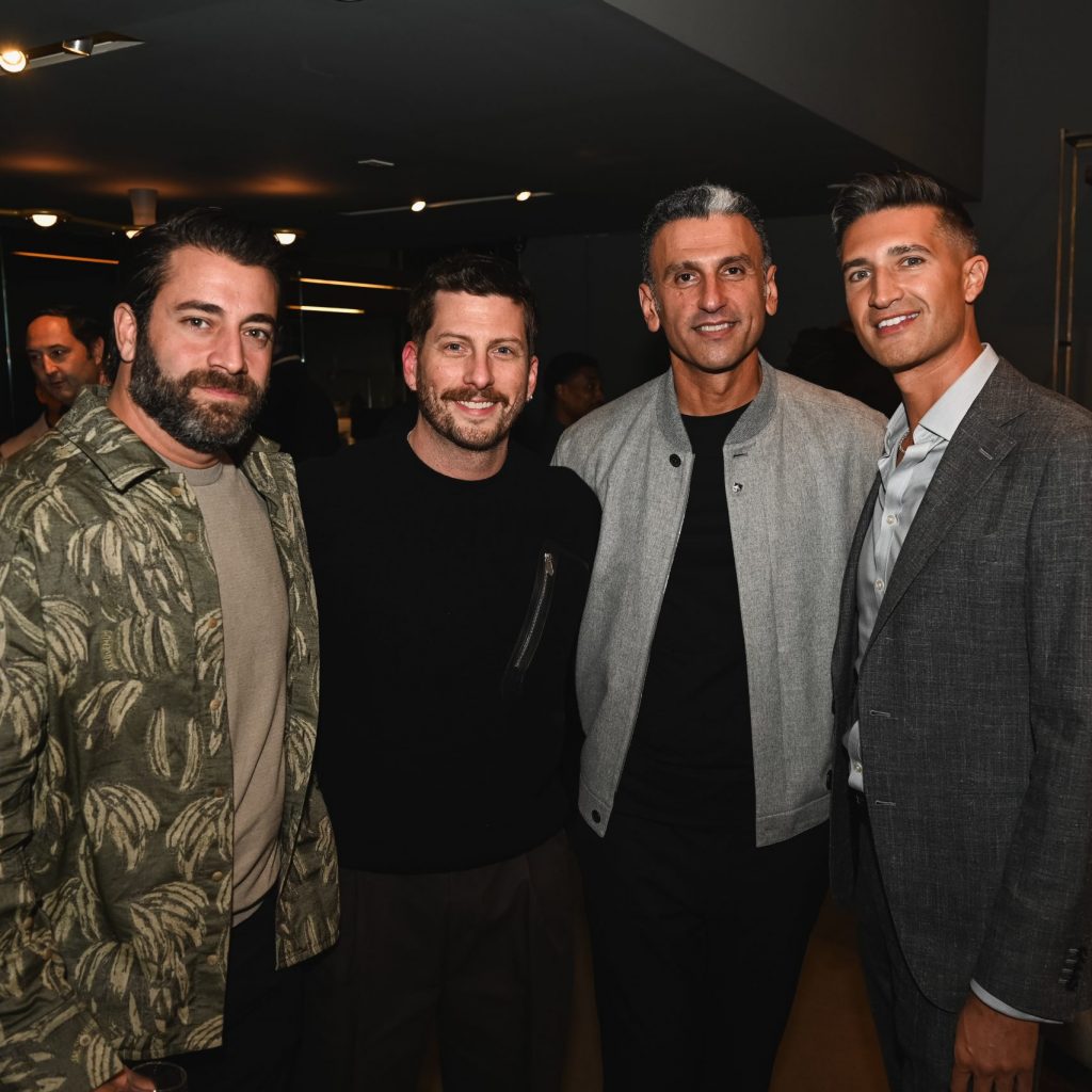 Four people pose together at an event in a modern interior, smiling warmly with soft lighting creating a relaxed and friendly atmosphere.