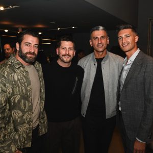 Four people pose together at an event in a modern interior, smiling warmly with soft lighting creating a relaxed and friendly atmosphere.