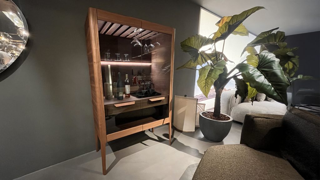 Atlante bar by Porada featuring a refined walnut frame with transparent glass panels interior LED illumination and a functional layout designed to display glassware bottles and bar tools with elegant craftsmanship.