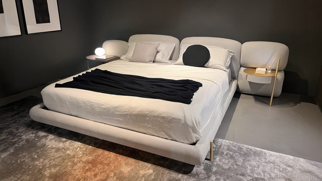 Stone Bed by Baxter shown with a softly upholstered low profile frame and segmented cushioned headboard creating a refined yet relaxed aesthetic that emphasizes comfort sculptural balance and understated luxury suitable for modern bedrooms.