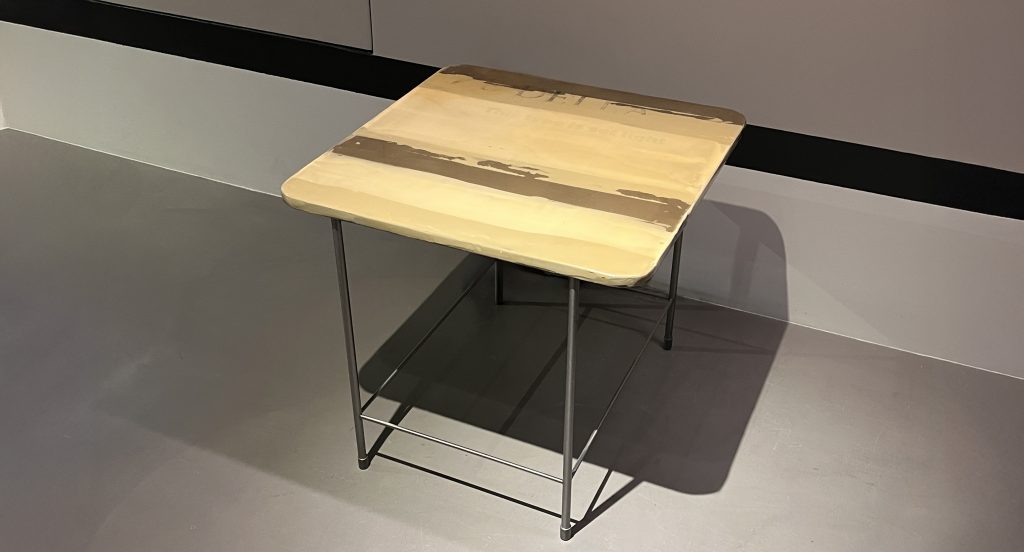 A compact side table featuring a warm yellow surface with a soft layered finish. The slim metal frame adds contrast and stability, making it a versatile accent piece for living areas, bedrooms, or reading corners.