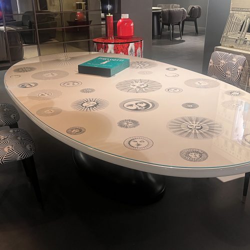 Oval Table Soli e Lune by Fornasetti featuring a glossy surface adorned with celestial faces and graphic motifs paired with a sculptural base creating an artistic yet elegant statement piece for refined interiors.