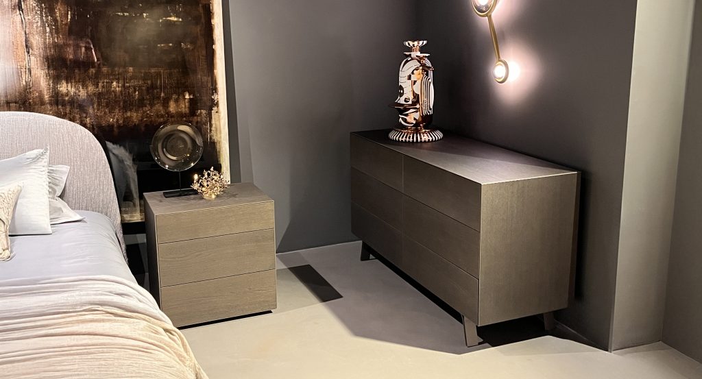 Matching dresser and nightstand in warm taupe wood with a soft matte finish. Clean lines and subtle grain are accented by dark legs, creating a calm, modern bedroom palette with neutral grays and warm metallic highlights.