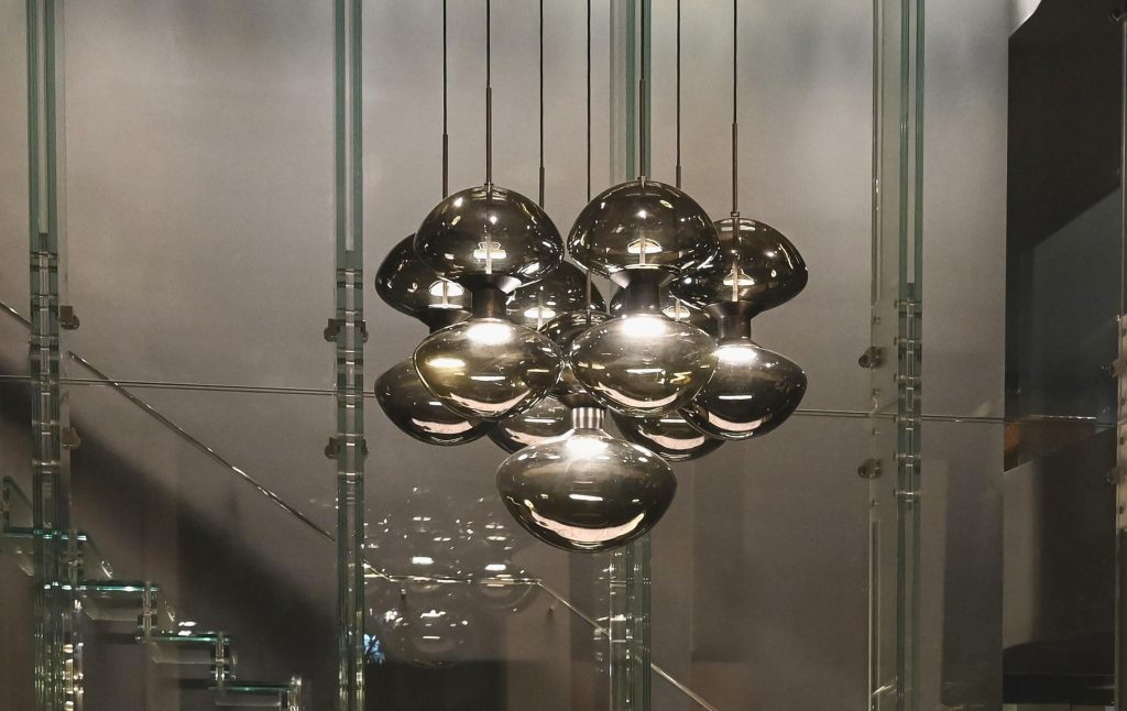 Suspended cluster of mirrored glass globes arranged in a compact composition that reflects its surroundings while emitting a warm layered glow ideal for statement lighting in modern and architectural spaces.