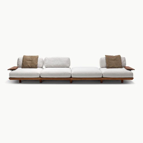 Wide modular Caprera sofa with soft neutral upholstery generous seating depth and refined wooden platform base creating a balanced blend of comfort and structure ideal for open contemporary interiors.