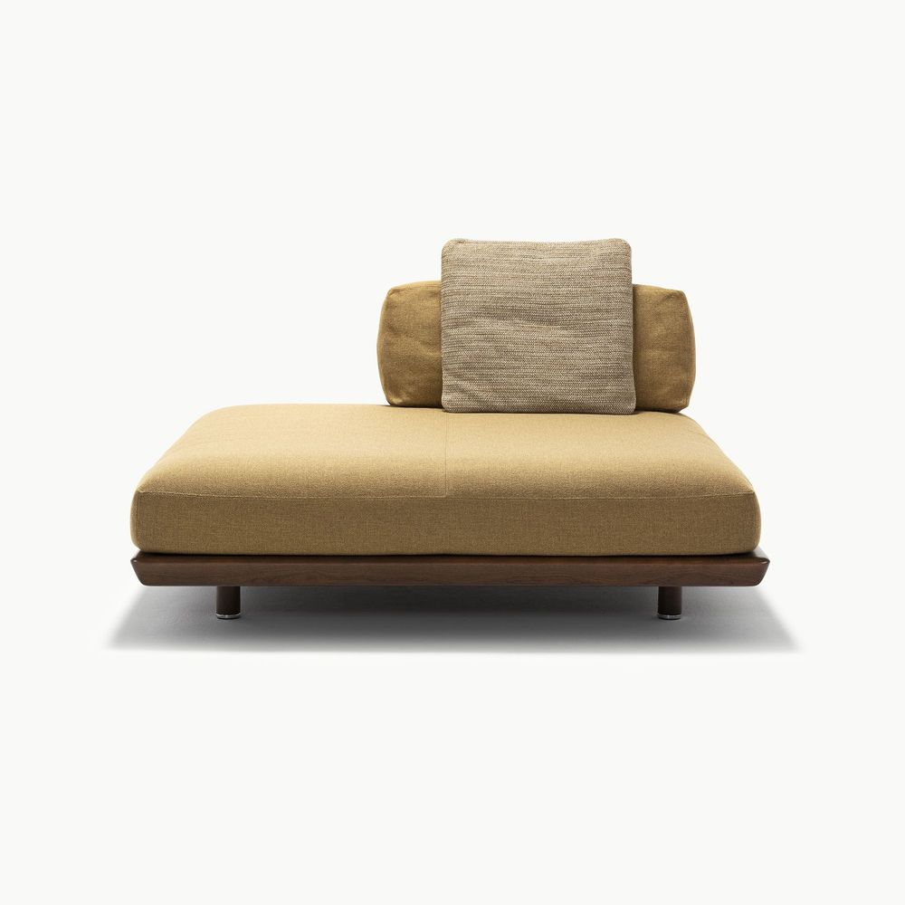 Caprera sofa module in warm beige upholstery with layered back cushions in tan and textured taupe resting on a dark wood base creating a balanced and inviting piece with soft tones and modern proportions.