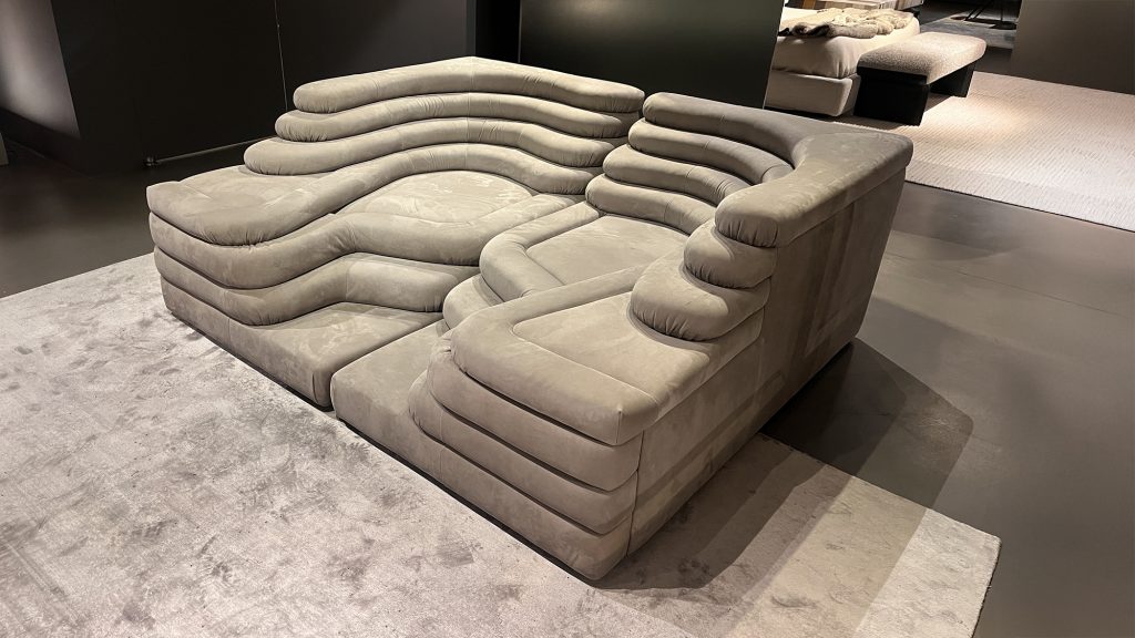 Curved modular sofa featuring generous padding, smooth organic lines, and plush upholstery designed to invite lounging, offering a bold yet understated silhouette that blends comfort, versatility, and modern design appeal.