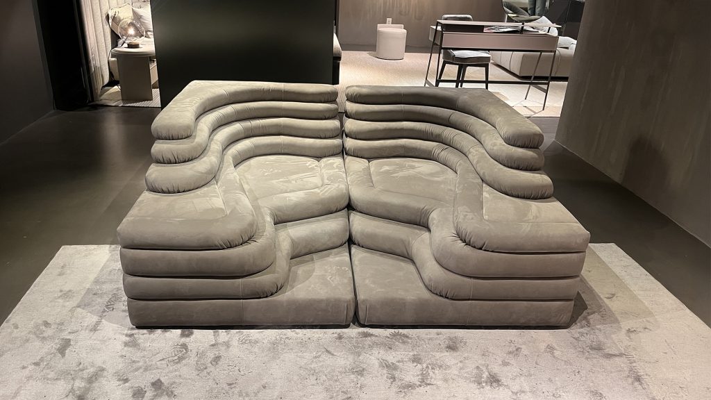 Low profile modular sofa with sculpted curves, layered cushioning, and soft upholstery creating a relaxed seating experience that emphasizes comfort, fluid form, and contemporary design character.