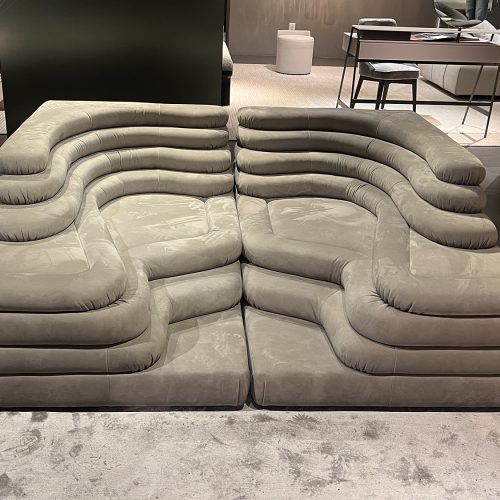 Low profile modular sofa with sculpted curves, layered cushioning, and soft upholstery creating a relaxed seating experience that emphasizes comfort, fluid form, and contemporary design character.