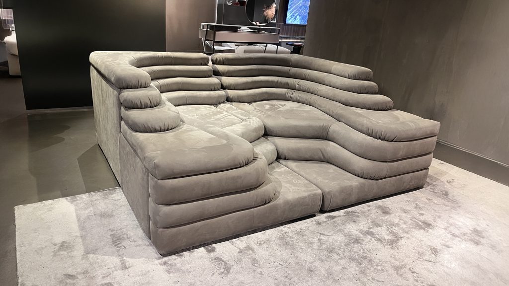 Modular sectional sofa with deep, layered cushions and rounded contours upholstered in soft suede like leather, creating a sculptural form that emphasizes comfort, flexibility, and relaxed lounging with a refined contemporary presence.