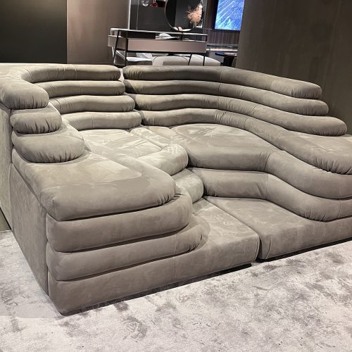Modular sectional sofa with deep, layered cushions and rounded contours upholstered in soft suede like leather, creating a sculptural form that emphasizes comfort, flexibility, and relaxed lounging with a refined contemporary presence.