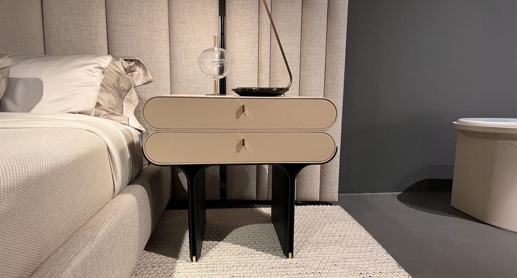 A sculptural bedside piece with two spacious drawers and smooth rounded corners. The warm beige finish pairs with slim gold hardware and a striking black base, giving this nightstand a clean modern look with a touch of luxury.