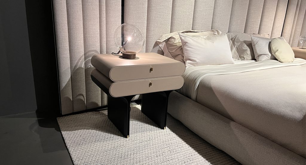 Designed with smooth curves and a compact silhouette, this two drawer nightstand brings a calm, modern feel to the bedroom. The warm neutral finish pairs beautifully with the bold black base, offering practical storage with a sculptural presence.