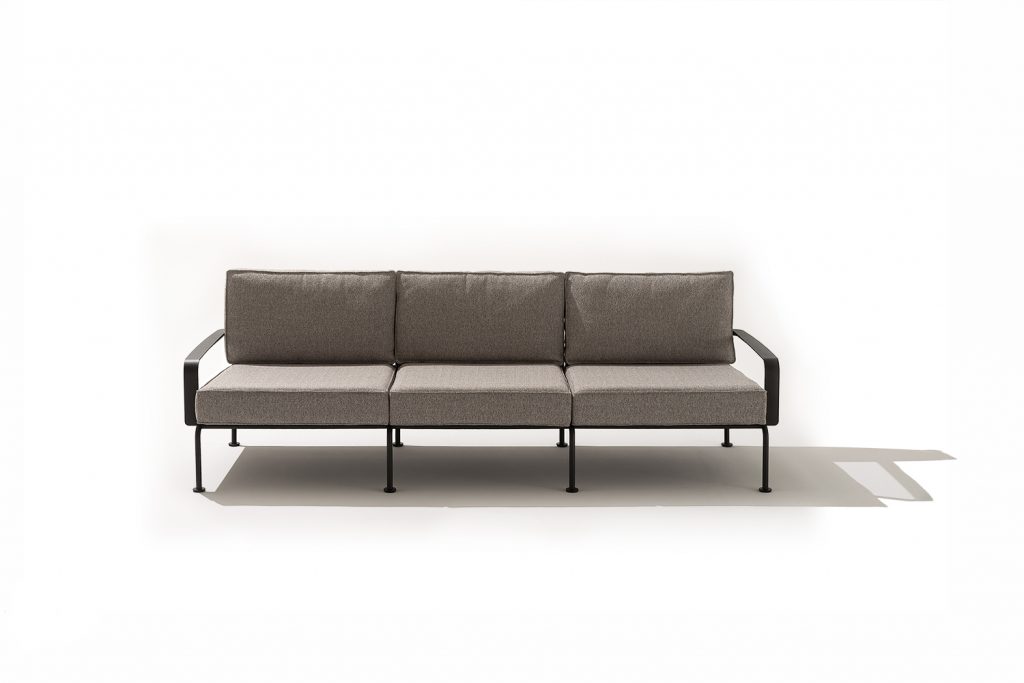 A streamlined outdoor sofa featuring clean lines, slim metal supports, and structured cushions. The balanced proportions and neutral tones create a light, modern presence suited for refined exterior or indoor spaces.